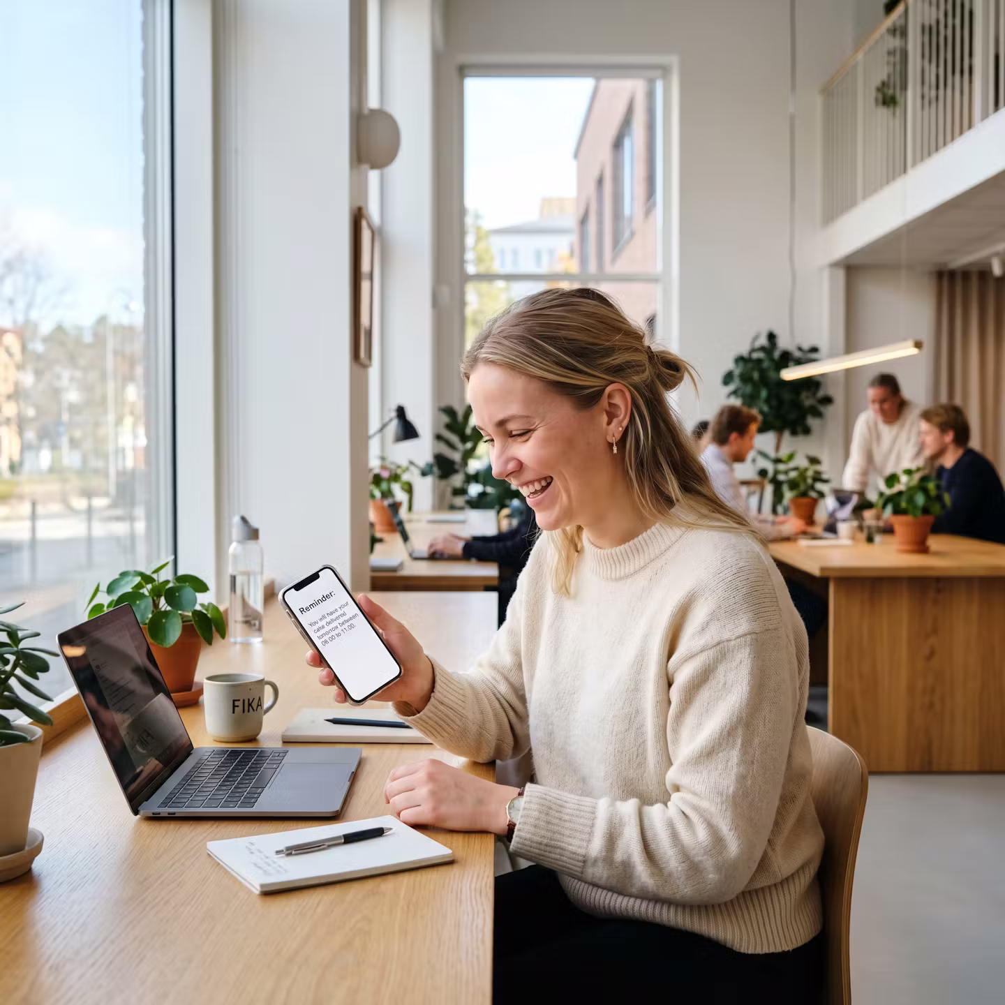 Person på kontoret som läser en påminnelse på mobilen om att tårtleverans sker nästa dag
